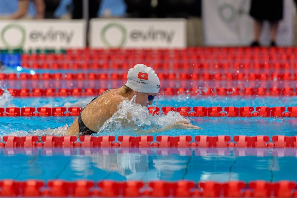 Brystsvømmer i AdO arena under Bergen Swim Festival 2026, med Eviny-bannere langs bassengkanten.